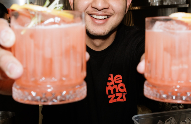 Barman of Demazzi Stone Grill holding two cocktails.
